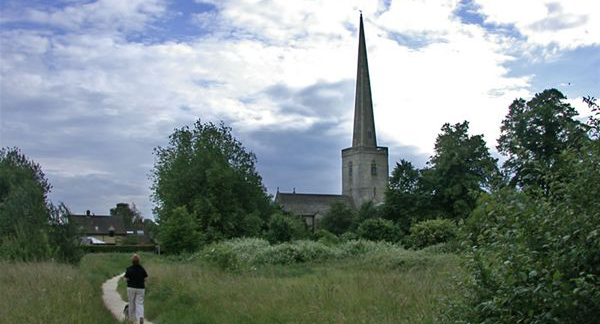 a path through a field with a church in the background